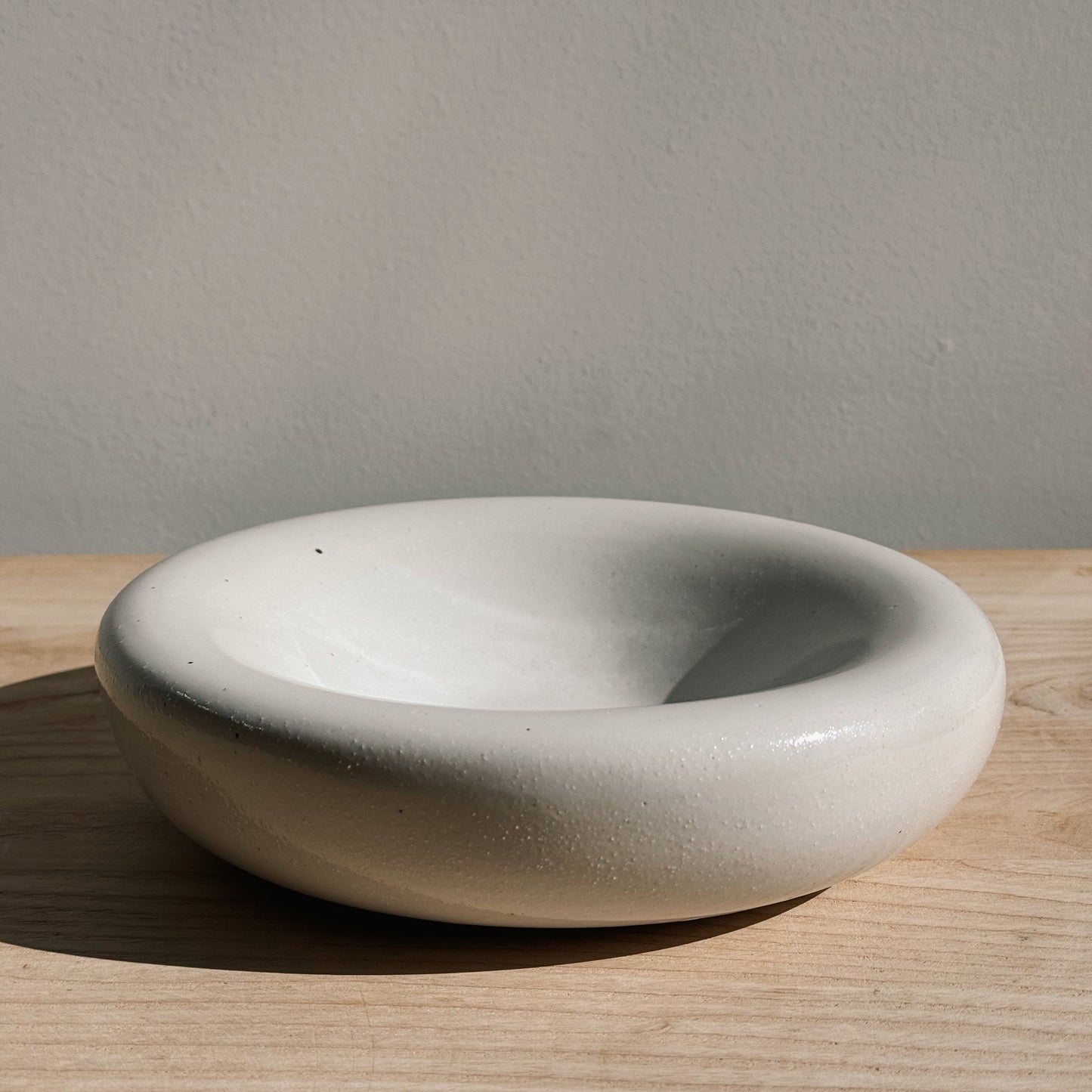 Handmade ceramic mug with a white background and black dots pattern, displayed on a wooden surface. Chubby Plate handcrafted stoneware