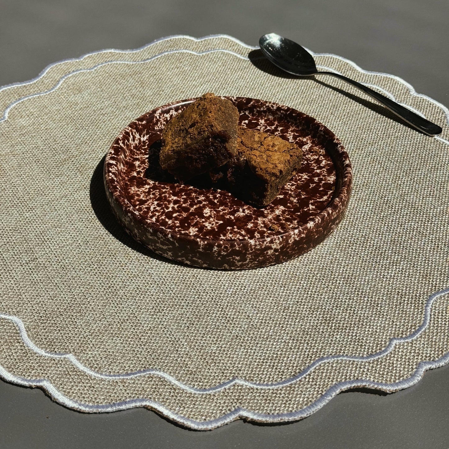 Chocolate cake with a scoop of brownie on a textured placemat with a spoon. Stoneware handmade ceramic plates, dessert plates.