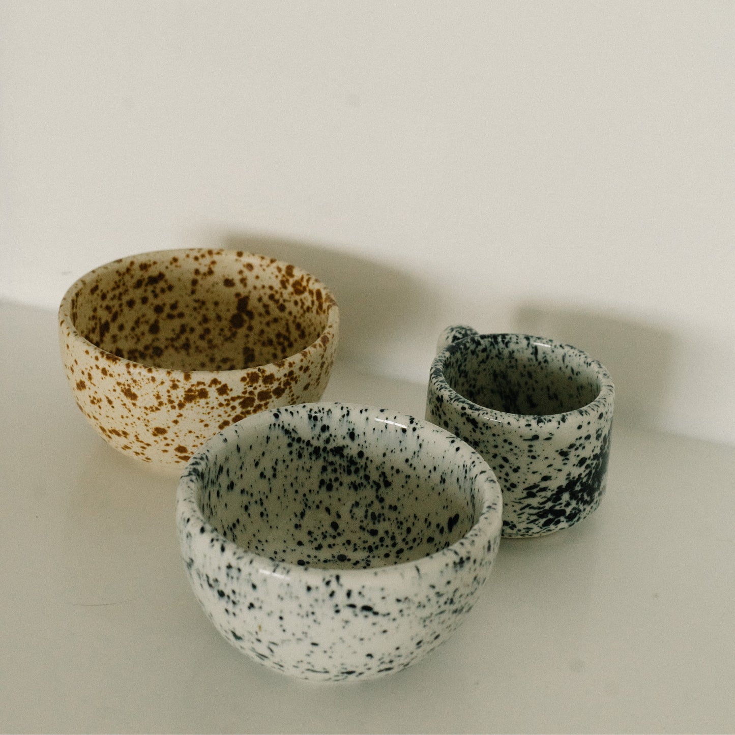 Three ceramic bowls with speckled patterns on a light background