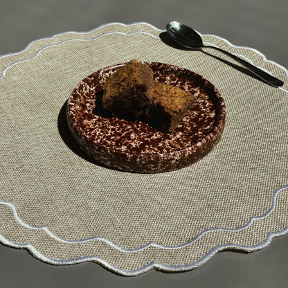 Chocolate cake with a scoop of brownie on a textured placemat with a spoon. Stoneware handmade ceramic plates, dessert plates.